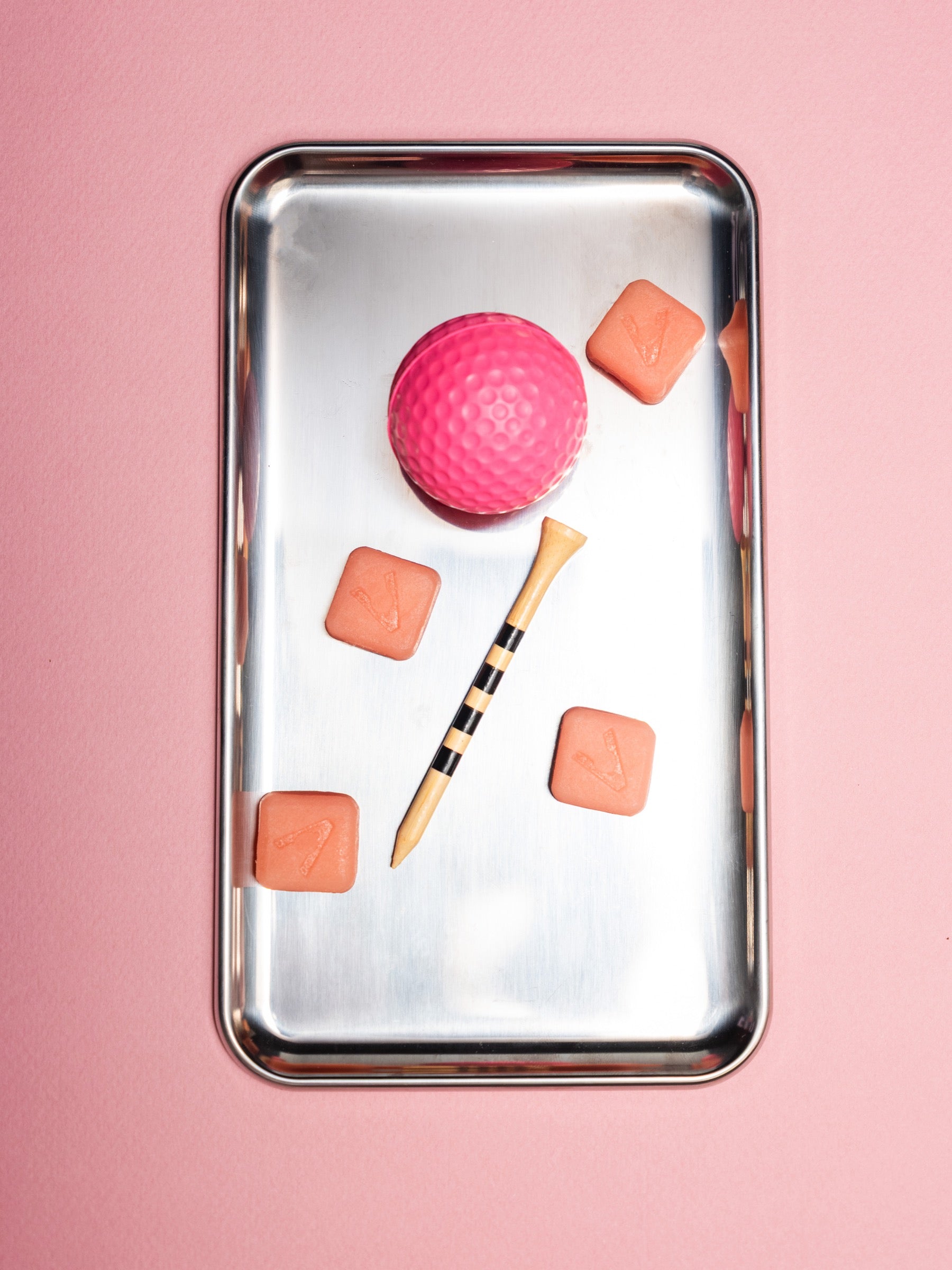Vybrance Labs watermelon creatine gummies on a steel tray with a pink golf ball and tee