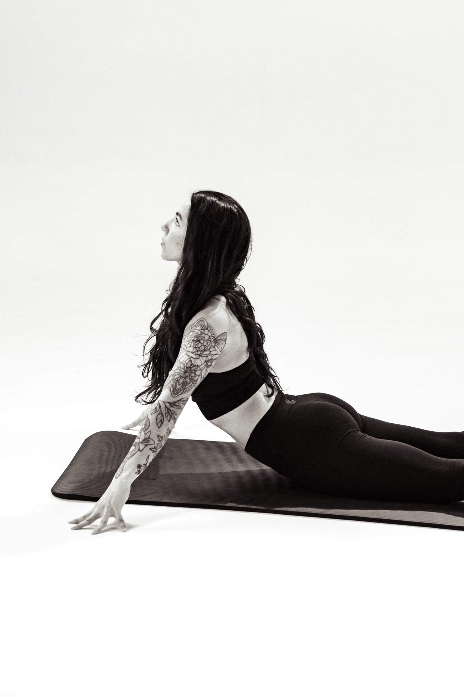 A woman on a mat in an upward facing stretch on a white studio backdrop