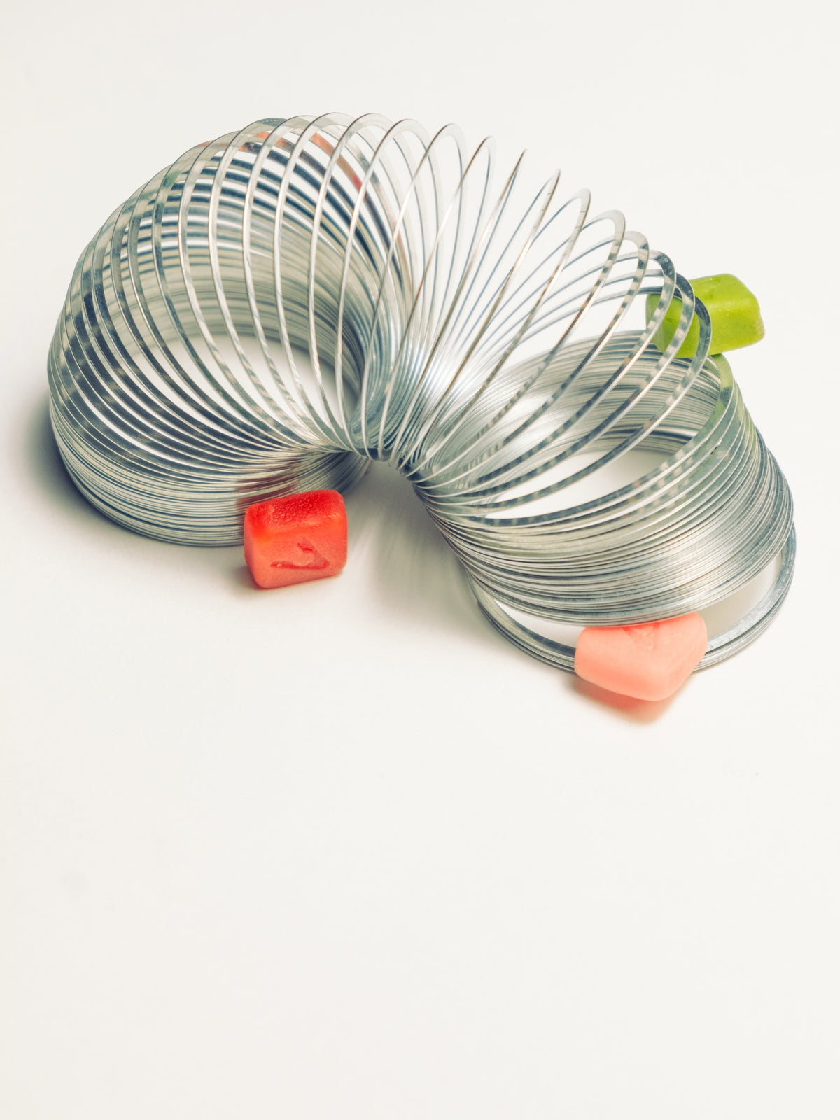 Three Vybrance Labs creatine gummies resting beside a coiled metal spring toy on a white surface